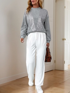 Close-up of grey sweatshirt with silver sequin patchwork and wide-leg white trousers