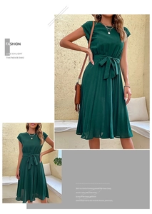 Detail of dark green pleated dress featuring a round neck and self-tie bow waistband