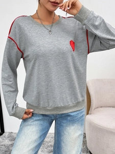 Close-up of grey sweatshirt featuring red heart embroidery and sleeve piping detail