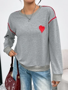 Detail of red heart embroidery and contrast piping on gray long sleeve sweatshirt
