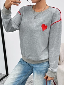 Detail shot of grey crewneck sweatshirt with red heart embroidery and sleeve stripes