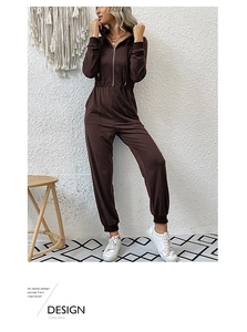 Detail of dark brown hooded long sleeve jumpsuit featuring zip-up front and elastic waist