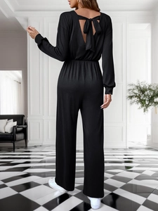 Detail of elegant black wide-leg jumpsuit with deep V-back and bow tie decoration