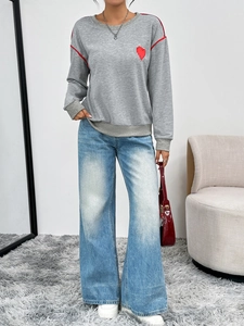 Detail of grey sweatshirt with red piping, heart patch and wide-leg denim jeans