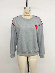 Detail of red heart embroidery and contrast piping on grey long-sleeved sweatshirt