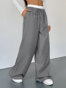 Dettaglio dei pantaloni a gamba larga a vita alta con strisce bianche e nere e coulisse