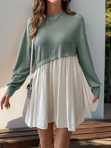 Detail of long sleeve color block dress featuring a green bodice and cream pleated skirt
