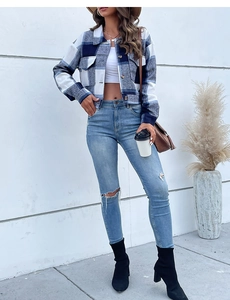 Detail of blue plaid flannel cropped jacket styled with high-waist ripped jeans and boots