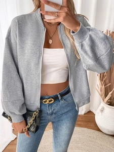 Close-up detail of grey zip-up fleece sweatshirt styled with white crop top and denim jeans
