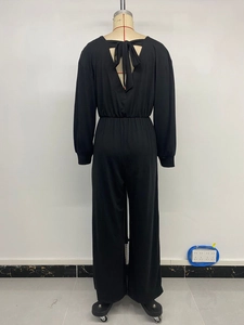 Detail of black long-sleeved jumpsuit featuring a back V-neck design with elegant bow tie