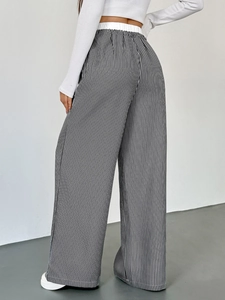 Dettaglio dei pantaloni a gamba larga a righe verticali bianche e nere con elastico in vita alta