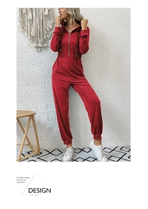 Detail of red hooded jumpsuit featuring zip closure and elastic waist on model