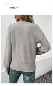 Detail view of the gray knitted sweater featuring exposed seams and ribbed hem at the back