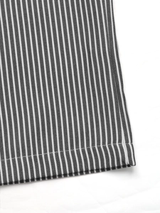 Dettaglio del tessuto a righe e delle cuciture rifinite sui pantaloni larghi a vita alta