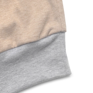 Detail shot of beige knit fabric spliced with gray ribbed texture on sweatshirt
