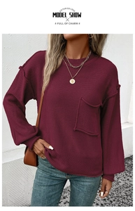 Detail of burgundy knit sweater featuring large pockets and decorative external stitching