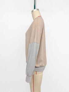 Detail view of crewneck sweatshirt showing apricot and grey color-block patchwork