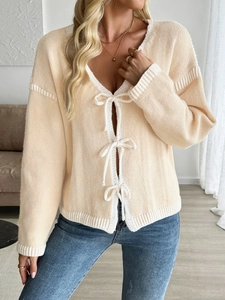 Detail of V-neck knit cardigan featuring white ribbon bows and ribbed contrast trim