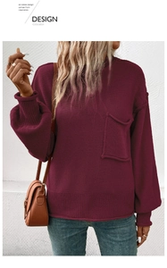 Detail of burgundy knit sweater showing ribbed cuffs and decorative front pocket