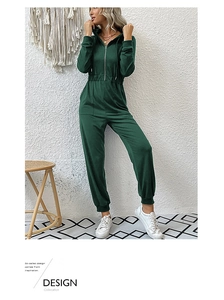 Detail of dark green hooded jumpsuit showing elastic waist and soft fabric texture