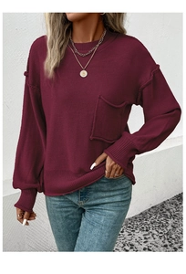 Detail of burgundy oversized knit sweater showing textured ribbing and decorative outer seams