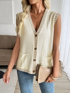 Close-up of contrast stripe trim and tortoiseshell buttons on a cream knit vest