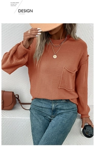 Close-up of brick red knit sweater with round neck, drop shoulders and a front pocket