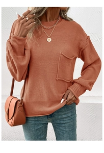 Detail of rust orange knit sweater showing the raw edge pocket and ribbed cuff textures