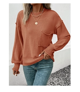 Detail of brick red knit sweater featuring a chest pocket and exposed seam design