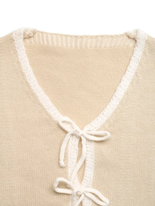 Detail of V-neck knit cardigan with bow tie closures and contrast white ribbed trim