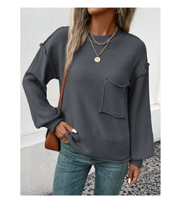 Close-up of charcoal gray knit sweater featuring a chest pocket and exposed seam detailing