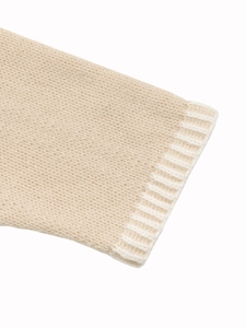 Detailed close-up of knit cardigan sleeve with white ribbed cuff and beige knit fabric