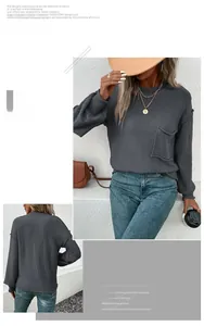Detail of dark grey knit sweater showing front pocket and raw edge stitching seams