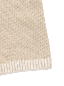Close-up of beige knit fabric texture and white ribbed hem detail on women sweater