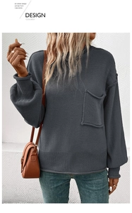 Detail of dark grey knit sweater showing chest pocket and ribbed lantern sleeves
