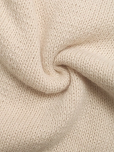 Macro detail of soft cream-colored knit fabric showing fine texture and plush wool yarn