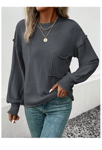 Detail of loose fit dark grey knit sweater featuring a chest pocket and ribbed textures