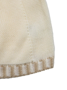 Close-up detail of cream and light brown ribbed knit texture on a sweater vest edge
