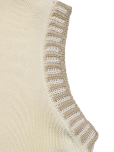 Detailed macro view of cream knitted vest armhole with contrast brown ribbed stitching
