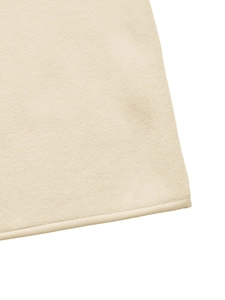 Detailed view of soft cream polar fleece fabric texture and smooth stitched edge finish