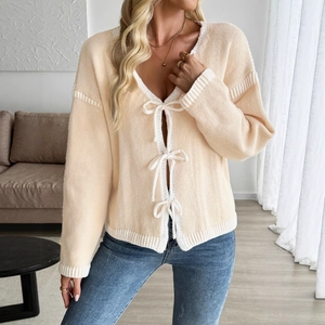 Chic beige V-neck knitted cardigan featuring white contrast trim and bow-tie closures