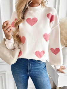 Nahaufnahme des cremefarbenen Strickpullovers mit rosa Herz-Jacquardmuster und Rippbündchen