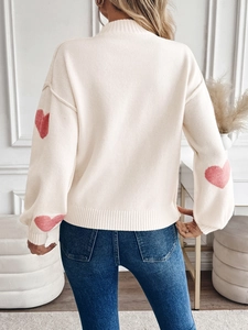 Detailansicht des cremefarbenen Rollkragenpullovers mit rosa Herz-Jacquard an den Ärmeln