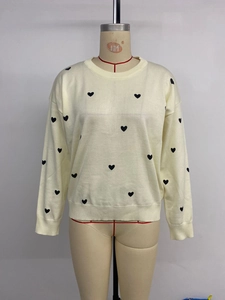 Close-up of heart jacquard pattern and ribbed knit cuffs on a cream sweater