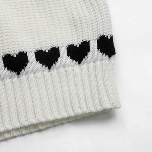 Dettaglio della manica in maglia bianca con motivi a cuori neri e polsino a coste