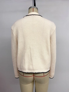 Détail du cardigan en maille côtelée crème avec bordure festonnée contrastée au dos