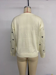 Detailed back view of off-white knitted sweater with black heart patterns on sleeves