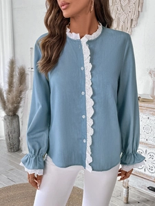 Detail view of the intricate white lace embroidery on a light blue puff sleeve shirt