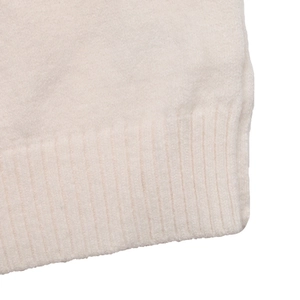 Nahaufnahme der Rippstrickbündchen und cremefarbenen Textur des Herz-Jacquard-Pullovers