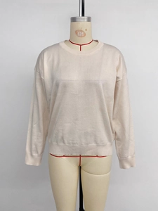 Close-up of beige knit sweater showing round neck detail and ribbed cuffs texture